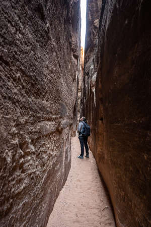 Woman Looks Up at Smooth Cliff Walls of the Slot Canyon on the Joint Trailの写真素材