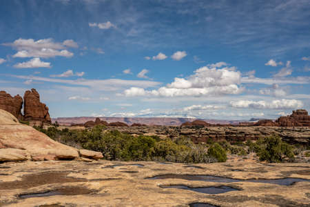 Potholes Filled With Water Dot The Cliff Edge Looking Toward The La Sal Mountains in Canyonlands National Parkの写真素材