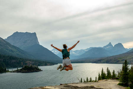Woman Jumps For Joy On The Edge of Saiint Mary Lake in Glacier National Parkの写真素材