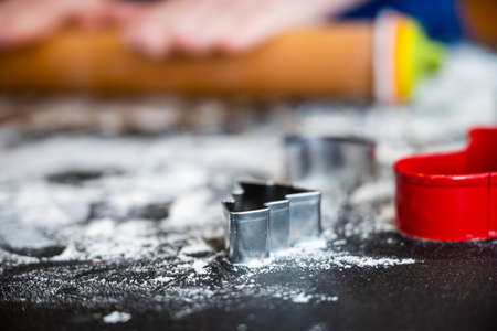Tiny christmas Cookie cutters sit on floured surface with rolling pin behindの写真素材