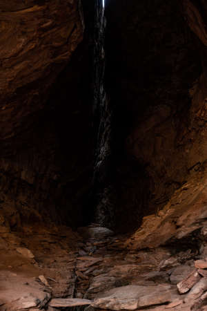 Shaft Of Light Breaks Through A Narrow Crack Of A Cave Ceiling in Canyonlands National Parkの写真素材