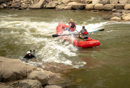 Durango, United States: May 29, 2022: Red Boat Floats A Rapid While Surfer Paddles to The Edge of...