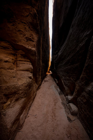 Sliver of A Cliff Face Glows Orange At The End of a Slot Canyon in Canyonlands National Parkの写真素材