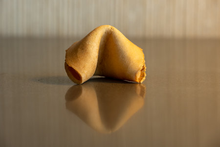 Single Fortune Cookie Sits Centered On Reflective Countertopの写真素材