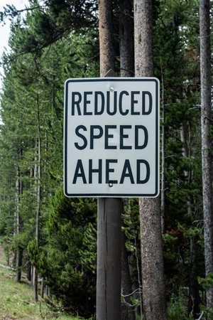 Reduced Speed Ahead Sign on Wooden Post in Yellowstone National Park