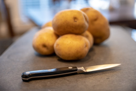 Paring Knife Sits On Cutting Board with Yukon Gold Potatoes on cutting boardの写真素材