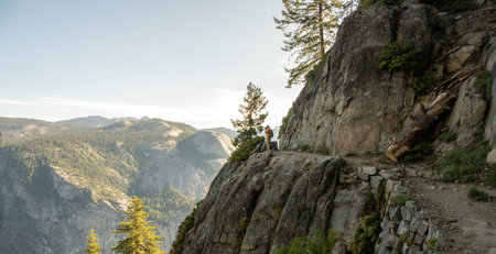 Hiker Stops to Take a Photograph on a Scenic Stretch of Four Mile Trail in Yosemiteの写真素材