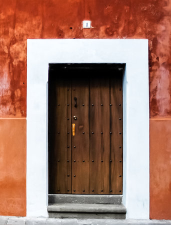 A wooden door is framed by white against a painted orange wallの写真素材