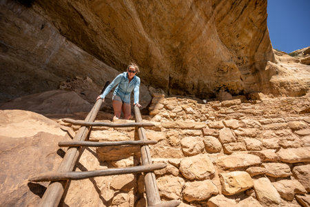 Woman Looks Down From Top Of Ladder In Mesa Verde National Parkの写真素材