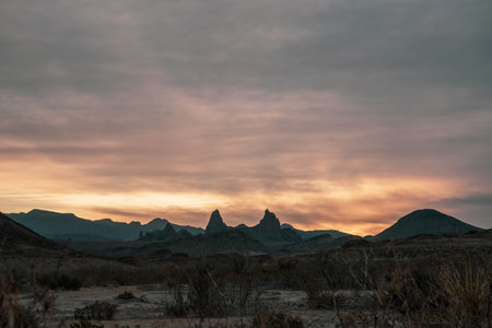 Sun Rises Into Thick Clouds Over Mule Ears In Big Bend National Parkの写真素材