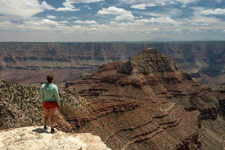 Woman Stands On The Edge And Looks Out Over The North Rim Of Grand Canyon in summerの写真素材