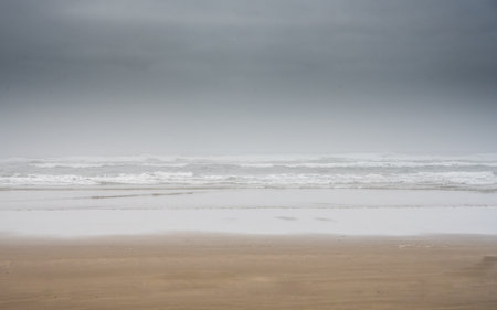 Wet Sand and Dark Clouds Fame The Pacific Surf Off Cannon Beach on Oregon coastの写真素材