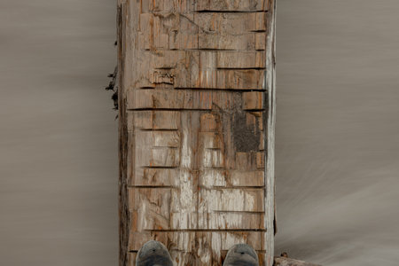Feet On Log Bridge Over Rushing Waterの写真素材