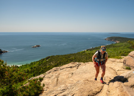 Woman Hikes Up Steep Rock Face Of The Beehive in Acadia National Parkの写真素材
