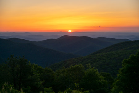 Sun Rises Over Horizon Behind Mountains in Summerの写真素材