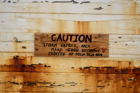 Caution Sign on Wooden Wall Indicates Prior Storm Damage in the area