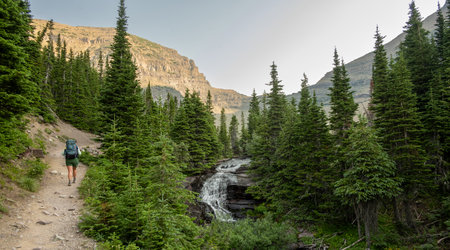 Backpacker Passes Cascade On Ptarmigan Creek in Glacier National Park