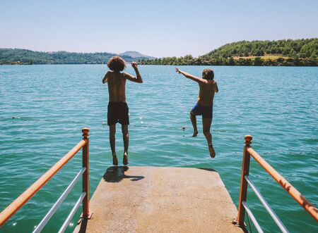 Children jumping into the lake in summer
