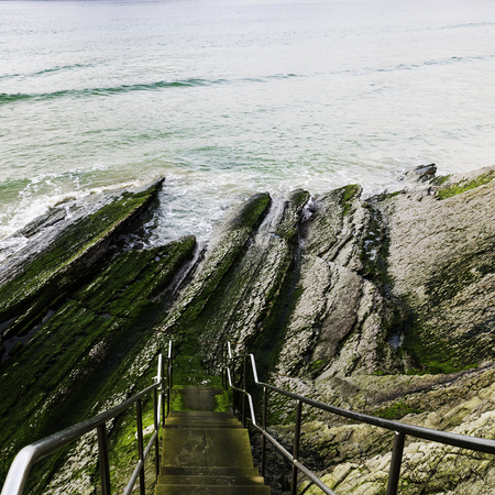 Stairs with banister descending for the cliff towards the beach in San Sebastianの写真素材