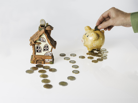 Hand putting  coin inside money box to buy a houseの写真素材