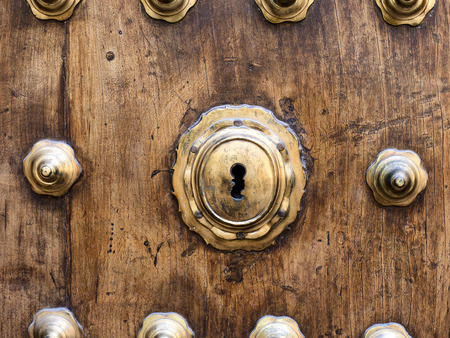 closeup keyhole on wooden rustic door with ornaments of base metalの写真素材