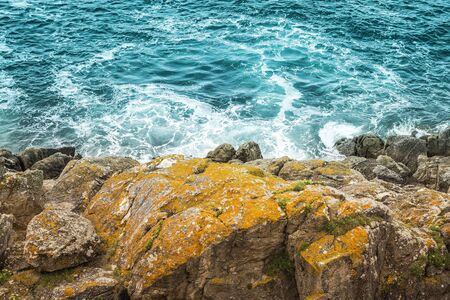 top view or yellow rocks on the rough sea