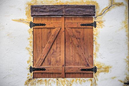 old fashioned wooden window closed on white rustic facadeの写真素材