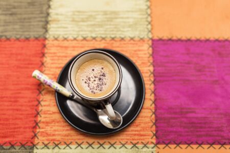 view from above of cup of milky coffee on a colorful tableclothの写真素材
