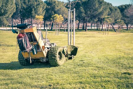 tractor mowing dirty grass after maintenance of a park meadowの写真素材