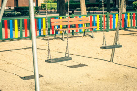 children's playground with empty swings suspended with steel chainsの写真素材