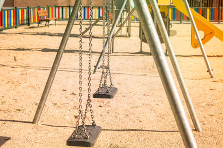 children's playground with empty swings suspended with steel chainsの写真素材