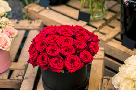 top view of group of red romantic roses into a black container on Wooden boards
