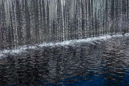 artificial waterfall with sunlit water dropletsの写真素材