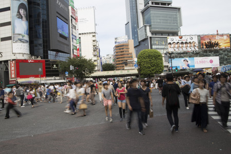TOKYO, JAPAN - July 10, 2016: Pedestrians walk at Shibuya Crossing. The scrambe crosswalk is one of the largest in the world.のeditorial素材