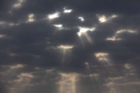 Sun rays through the dark clouds in the sky. Abstract background.