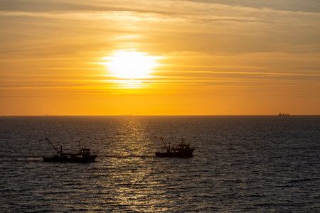 Fishing trawlers in the sea at sunset in the eveningの写真素材