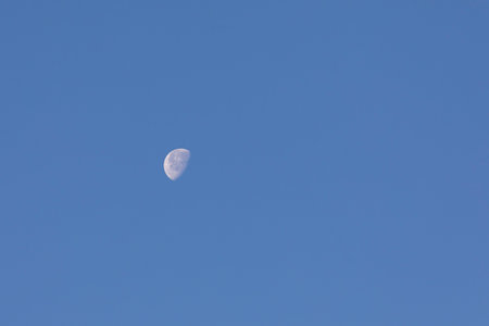 Moon in the blue sky with white clouds, closeup of photoの写真素材