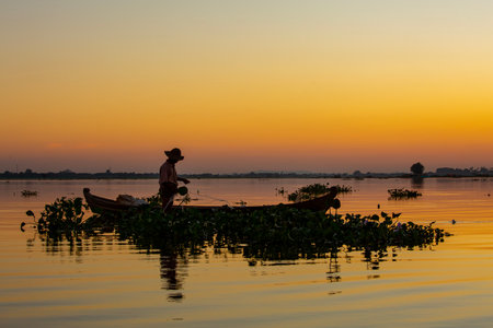 Fisherman in the boat on the river at sunset