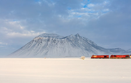 landscape with a red train on the background of snowy mountainsの写真素材