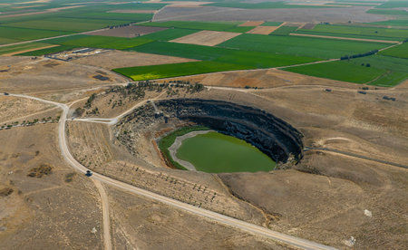 Aerial view of a large pit with a small lake in the middleの写真素材