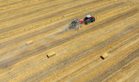 Aerial view of the tractor working on the large wheat field.の写真素材