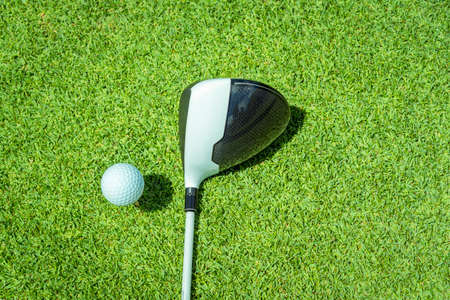 Golfer is putting golf ball on green grass at golf course for game with blur background and sunlight rayの写真素材