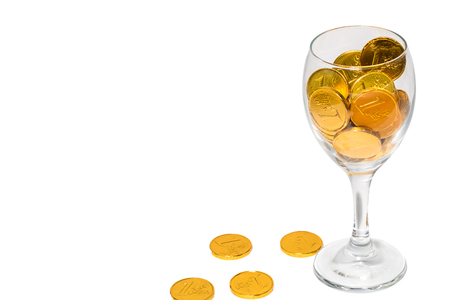 Glass of champagne with Overflowing golden coins, isolated on the white background の写真素材