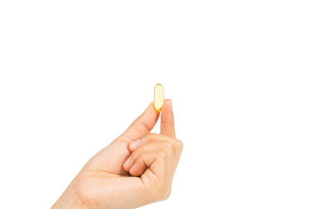 Woman's hand holding Fish oil capsules with omega 3 and vitamin D healthy diet concept, isolated on white background with clipping path.の写真素材