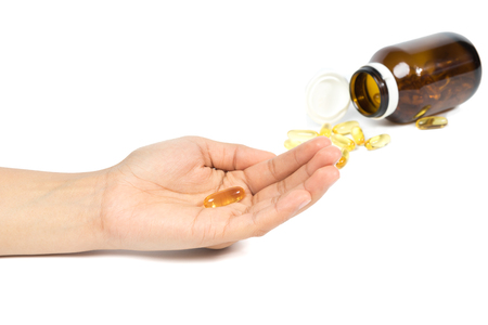 Woman's hand holding Fish oil capsules with omega 3 and vitamin D healthy diet concept, isolated on white background.の写真素材