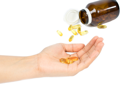 Woman's hand holding Fish oil capsules with omega 3 and vitamin D healthy diet concept, isolated on white background.の写真素材