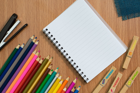 Blank notebook ,colorful pensils and Stapler on wooden desk for any idea on desk work.の写真素材