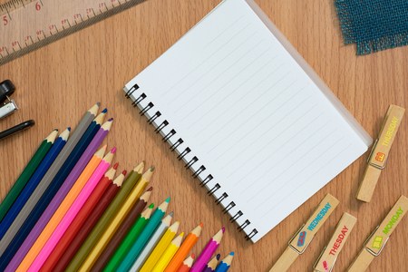 Blank notebook ,colorful pensils and Stapler on wooden desk for any idea on desk work.の写真素材