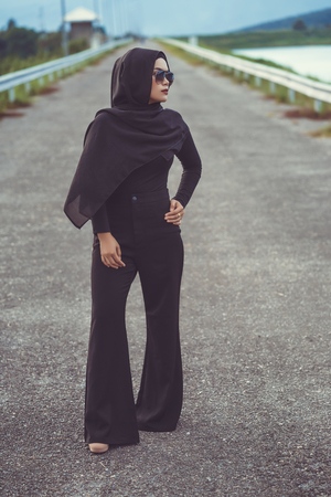Fashion portrait of young beautiful muslim woman with the black hijab and full black dress.Vintage styleの写真素材
