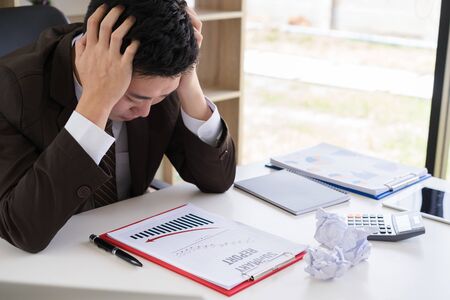 Depressed business man looking down when inspection about point of profit loss on business report. Negative human emotion facial expression feelings.の写真素材